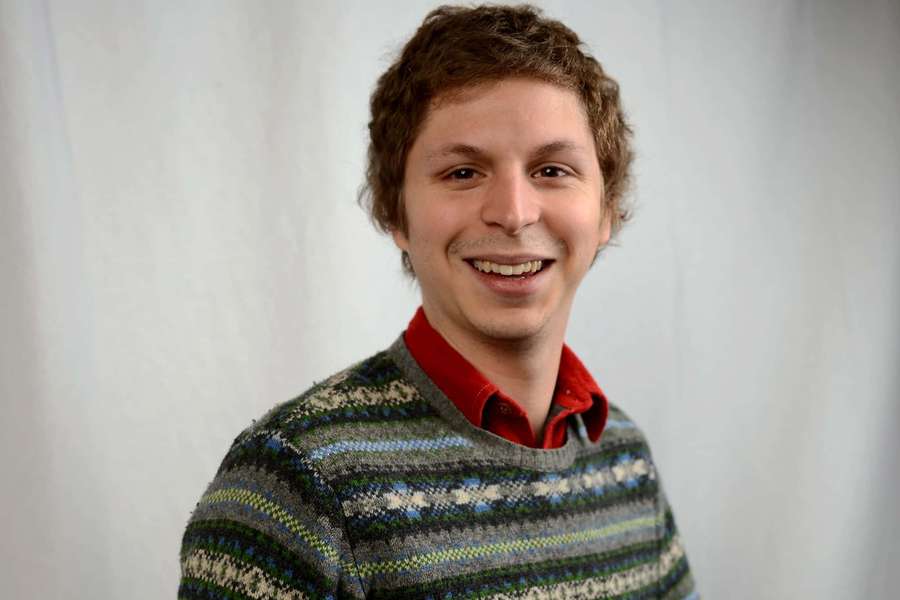 Nuori mies kuvioidussa villapaidassa hymyilee kameralle studiossa — Michael cera Taustakuvat