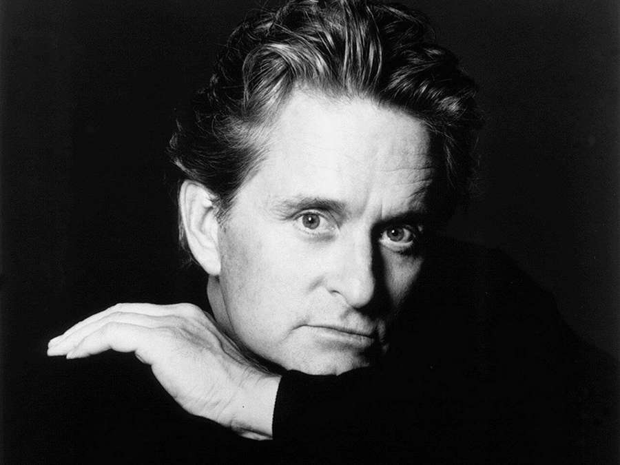 A man with intense eyes rests his chin on his hand in a black and white studio portrait. — Michael Douglas Wallpaper