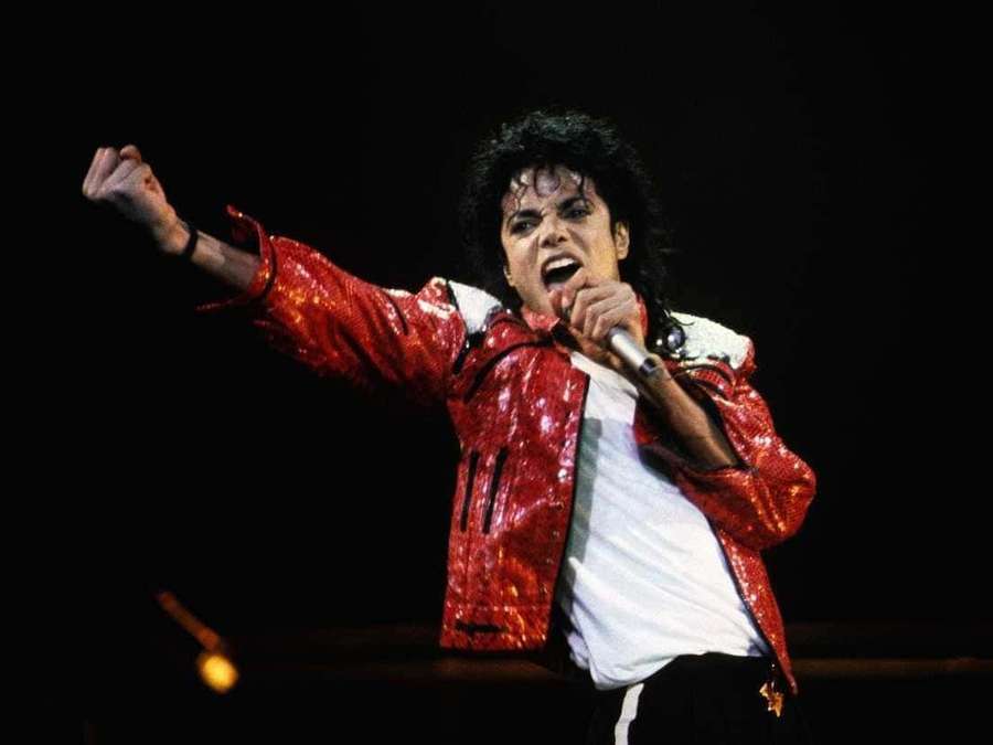 Michael Jackson singing on stage in a red sequined jacket with one arm raised. — Michael Jackson Background