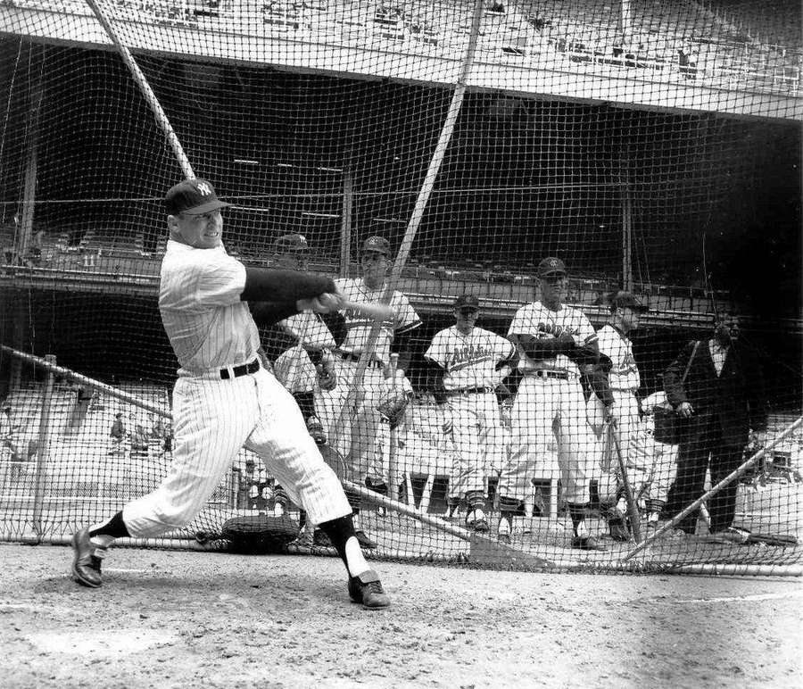 Baseball player swinging bat in batting cage with teammates watching — Mickey Mantle Background