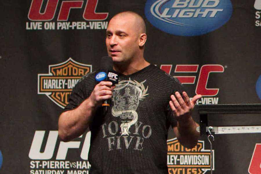 Lutador do UFC falando em uma coletiva de imprensa com banners de patrocinadores atrás. — Microfone Papéis de Parede