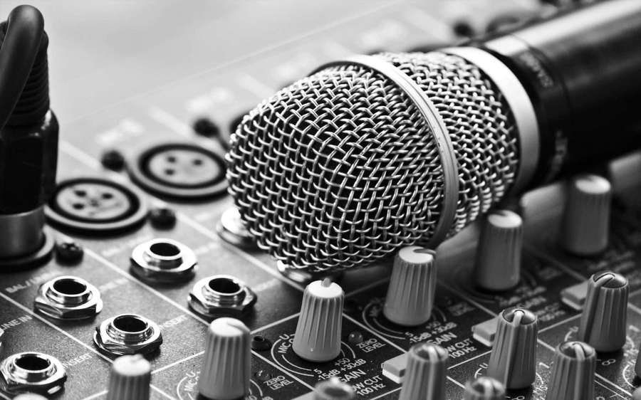 Professional microphone on audio mixing board with knobs and inputs. — Microphone Background