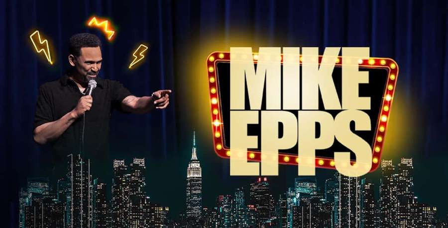 Comedian Mike Epps performing stand-up comedy on stage with a lit sign and city skyline behind him. — Mike Epps Picture