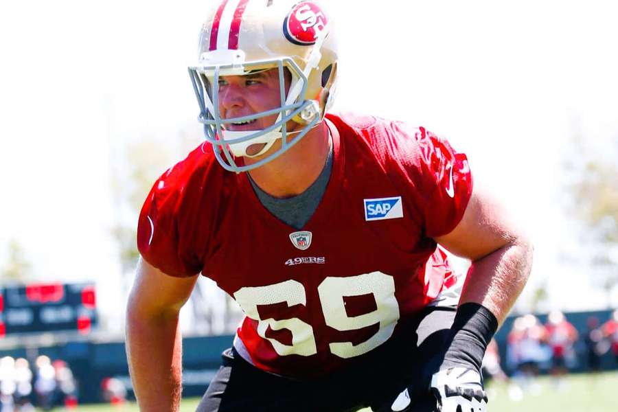 Football player in red jersey number 59 crouching on field during sunset. — Mike Mcglinchey Wallpaper