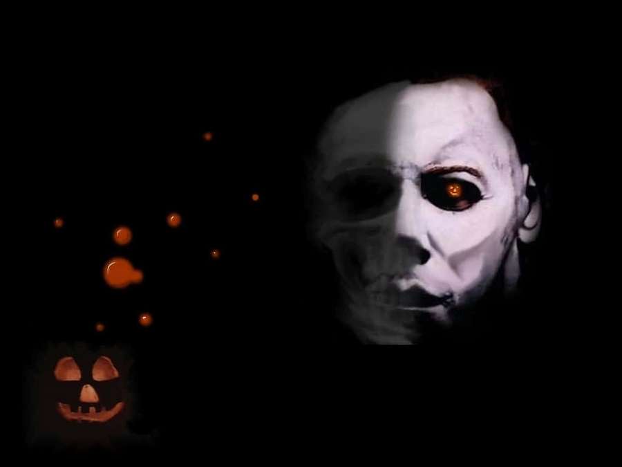 A masked horror figure with glowing eyes beside a lit jack-o'-lantern in darkness. — Mike Myers Wallpaper