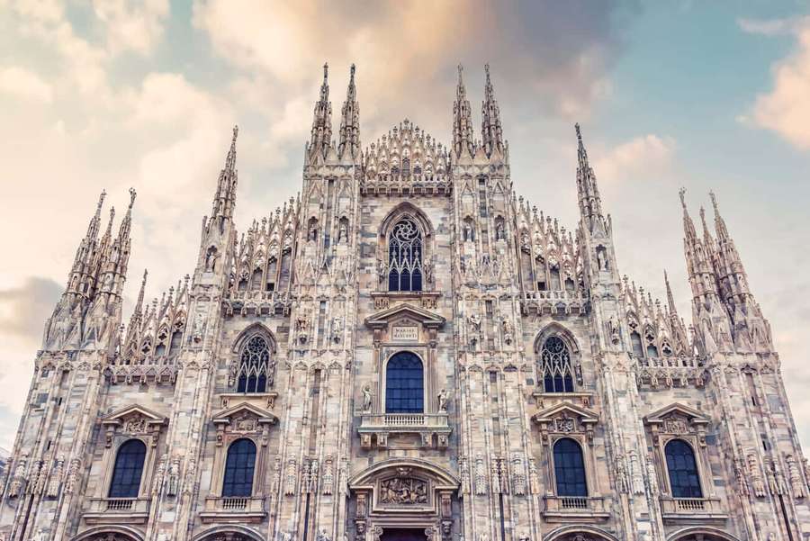 Gothic cathedral with spires and detailed stonework under a cloudy sky. — Milan Cathedral Wallpaper