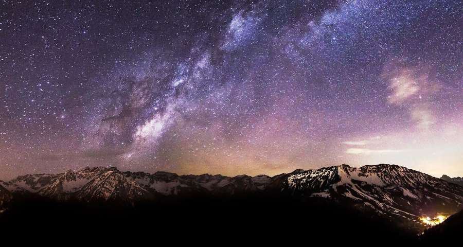 Snowy mountains under a vibrant starry sky with Milky Way and distant lights. — Milky Way Background