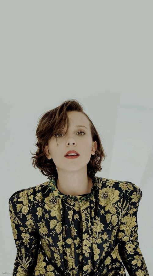Woman in black and gold floral blouse looking upward in studio setting — Millie Picture