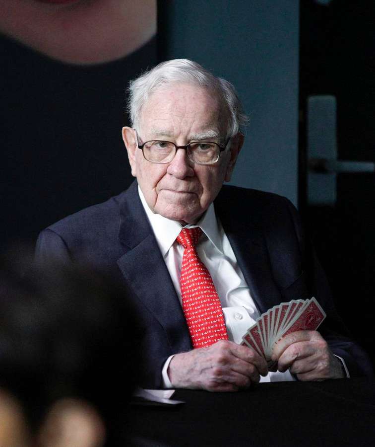 Warren Buffett sosteniendo naipes con un traje formal en interiores. — Millonario Fondos de pantalla