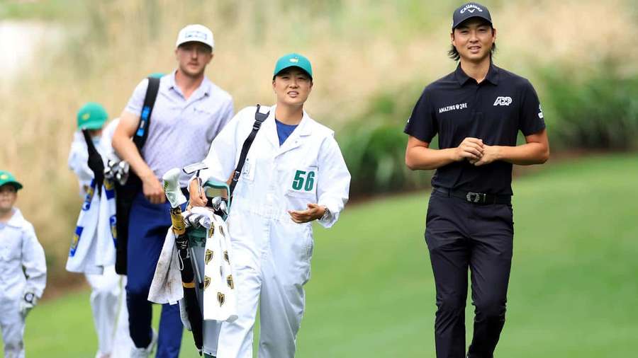 Golfers and caddies walking on a green course during a tournament. — Min Woo Lee Wallpaper