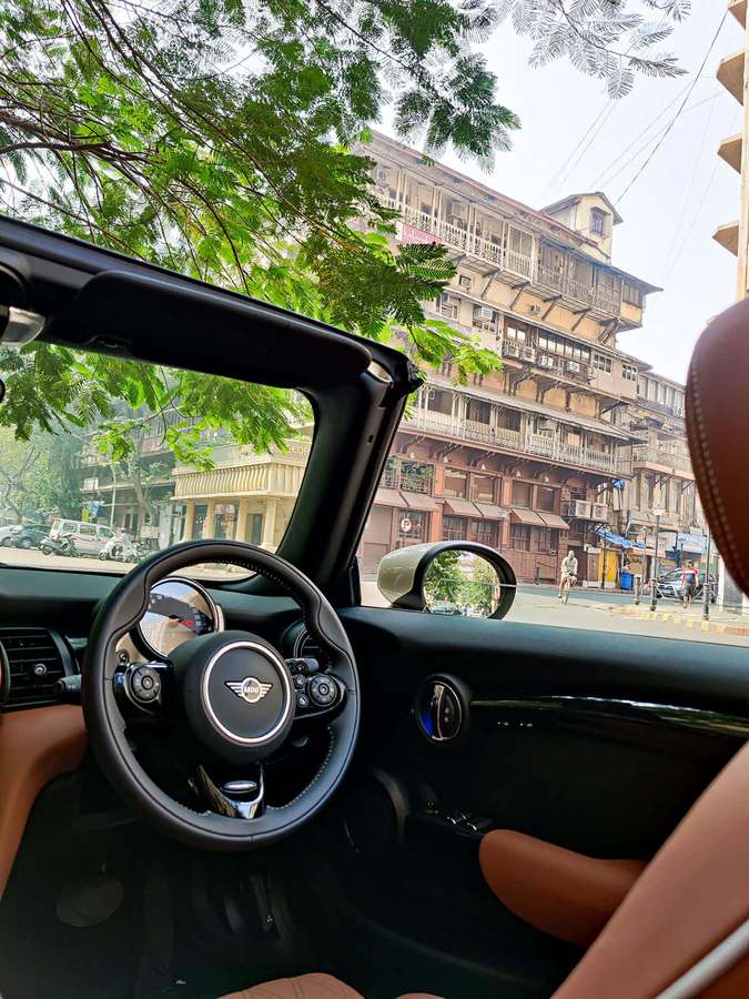 Interior of a convertible car with view of trees and urban buildings. — Mini Cooper Se Wallpaper