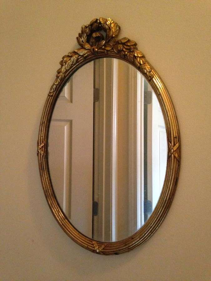 Vintage gold mirror with leafy top hanging on beige wall reflecting white door. — Mirror Background