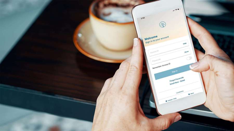 Person logging into an app with a coffee cup nearby. — Mobile Banking Wallpaper