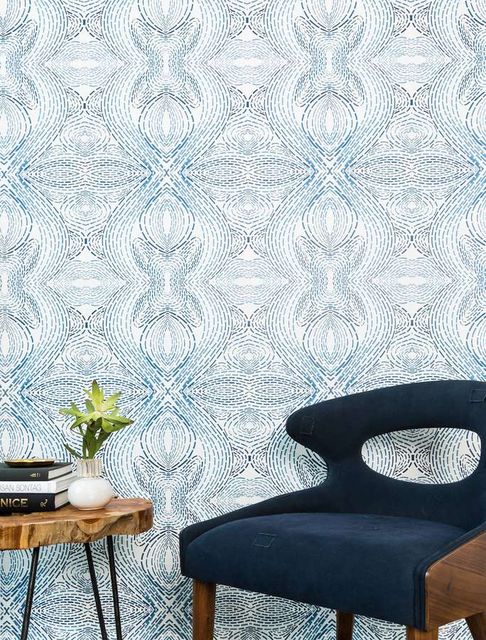 Dunkelblauer Stuhl neben Holztisch mit Pflanze und Büchern vor gemusterter Wand. — Mobiliar Wallpaper