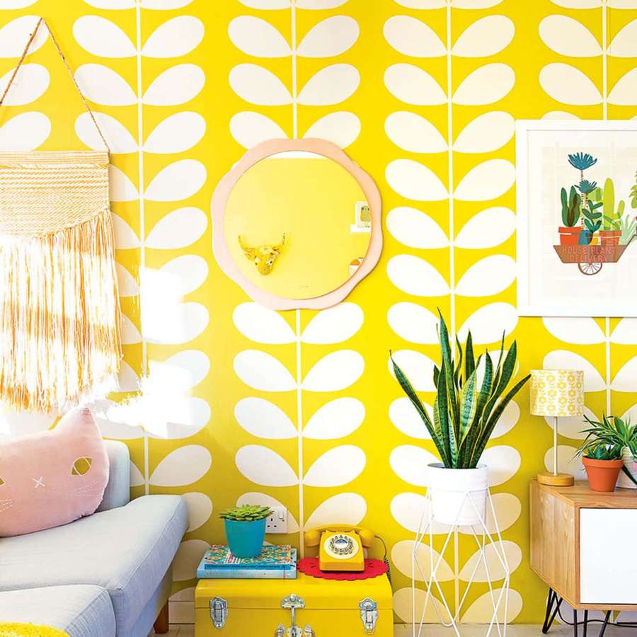 Quarto aconchegante com papel de parede amarelo de folhas e decoração retrô incluindo macramê pendurado na parede e planta cobra. — Moderno Papéis de Parede