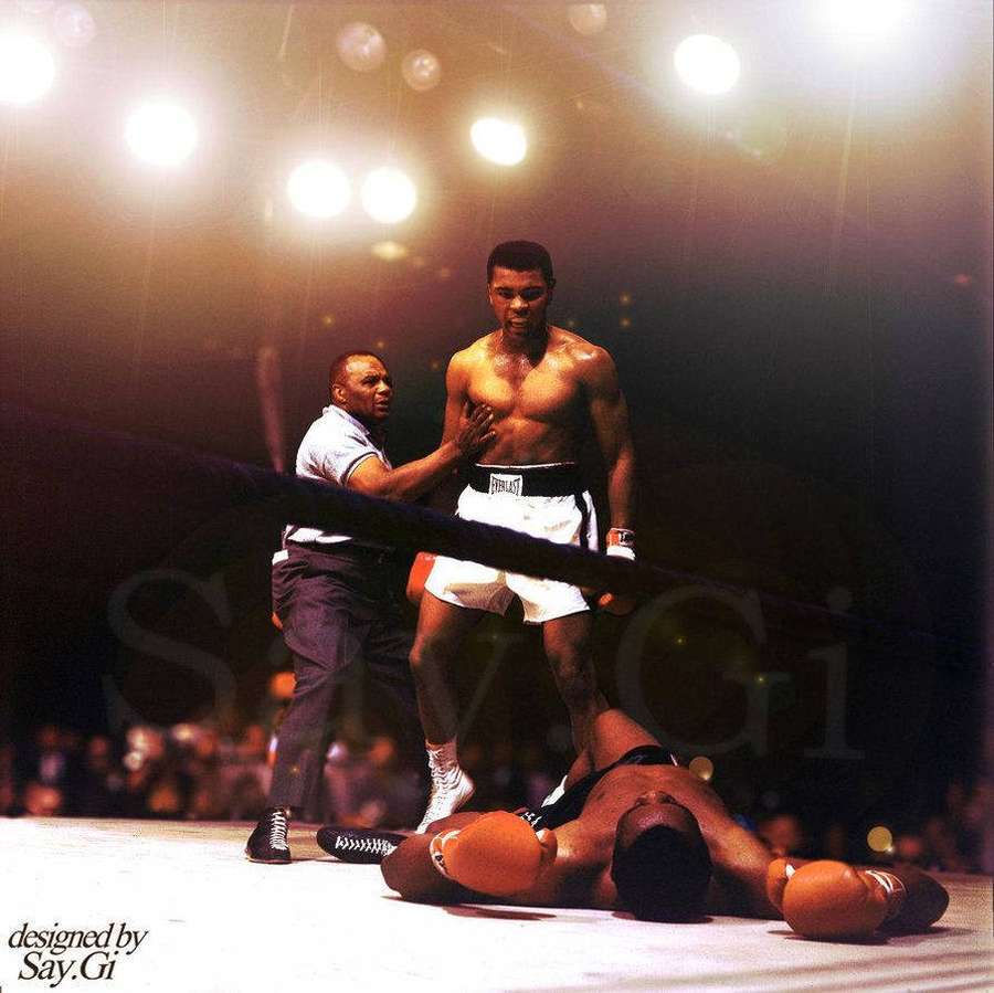 Boxeador em pé vitorioso sobre oponente caído no ringue sob luzes brilhantes. — Mohammed Ali Papéis de Parede