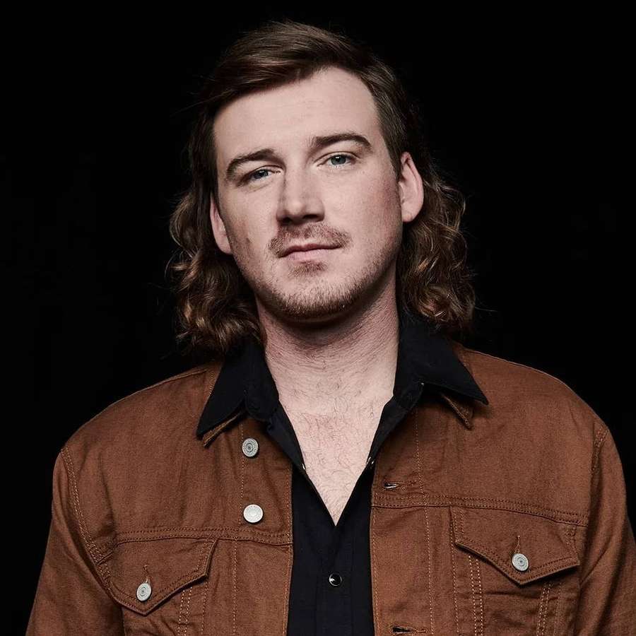 Man with long brown hair and beard wearing brown jacket and black shirt. — Morgan Wallen Wallpaper