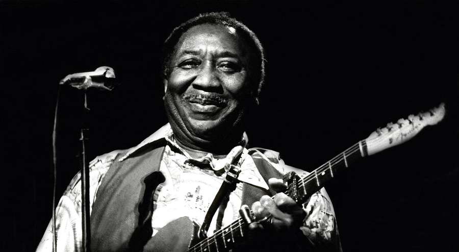 Black musician playing electric guitar on stage with microphone — Muddy Waters Wallpaper
