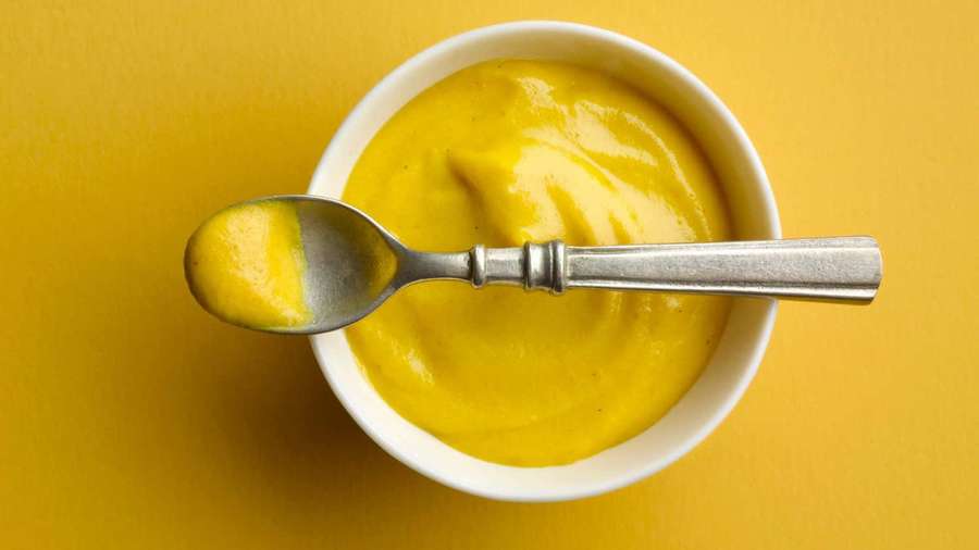 White bowl of yellow puree with silver spoon resting on rim. — Mustard Wallpaper