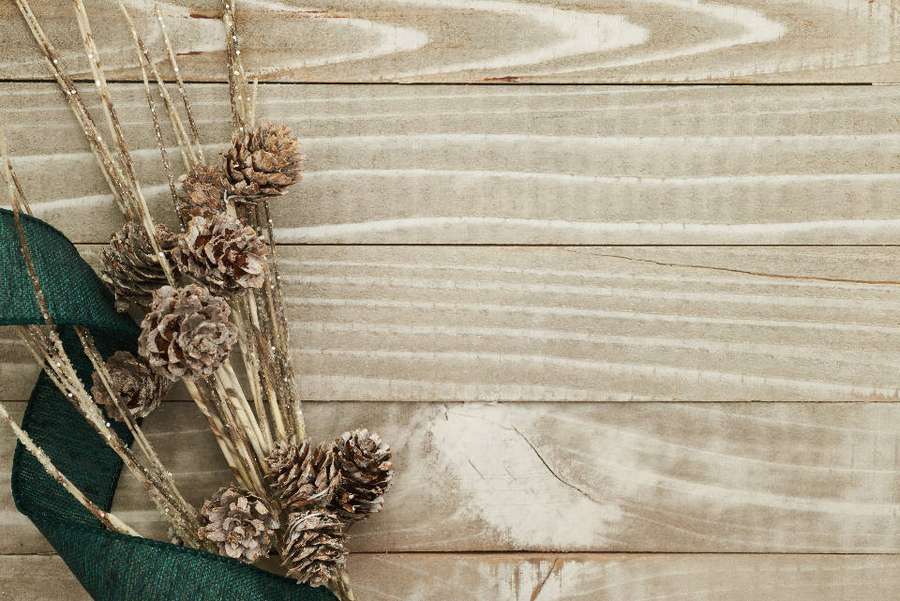 Pinhas secas e galhos amarrados com fita verde em superfície de madeira. — Natal rústico Papéis de Parede