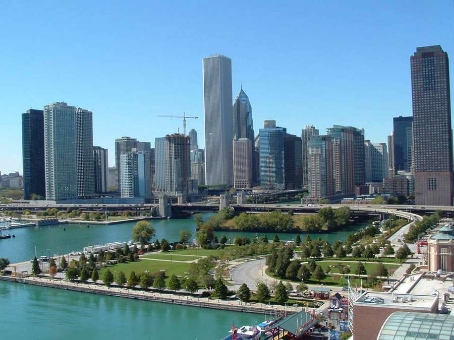 Chicago skyline with tall buildings, river, and green park under clear blue sky. — Navy Pier Background