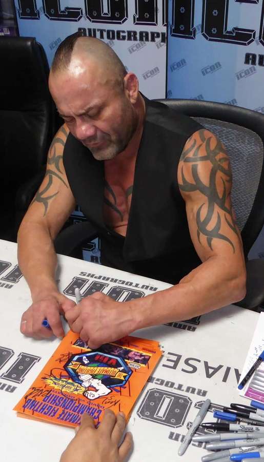 Wrestler signing autographs for fans at a convention table. — NBA Tattoos Picture