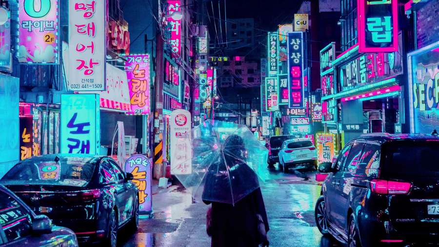 Person walking under umbrella in rainy neon-lit Korean city street at night. — Neon Street Wallpaper