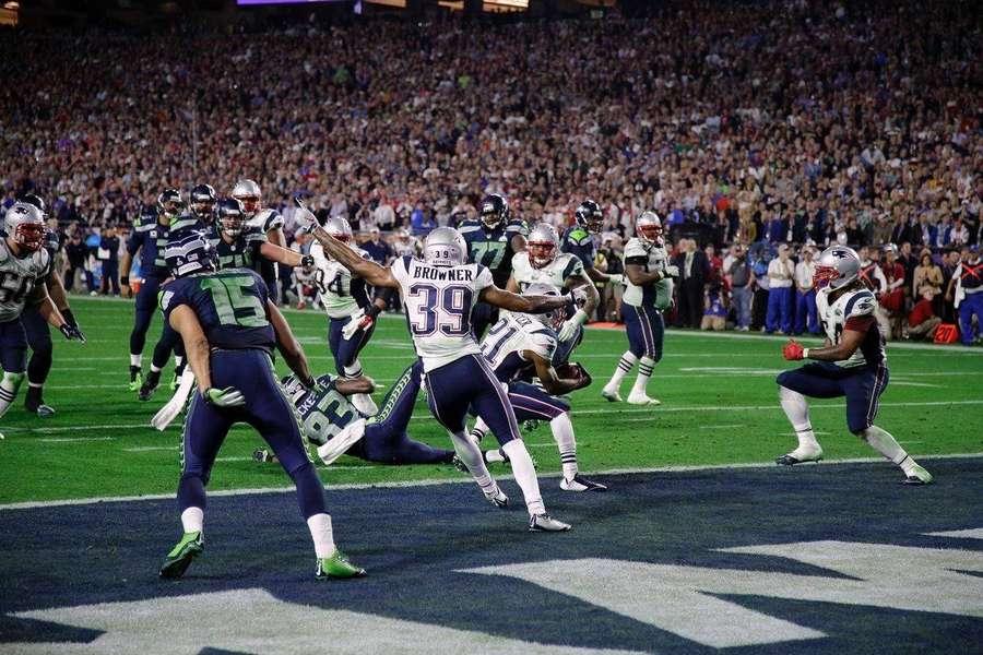 Footballspieler konkurrieren während eines Nachtspiels in einem vollen Stadion. — New England Patriots Wallpaper