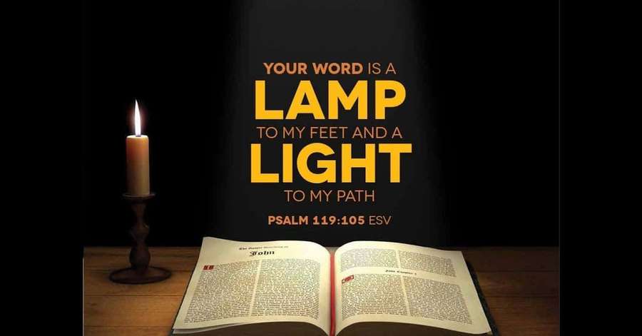Open Bible with candlelight illuminating scripture text on wooden table. — New Testament Wallpaper