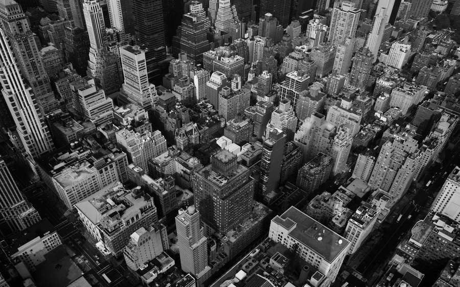 Aerial black and white photo of a dense city with skyscrapers and streets. — New York Black And White Background