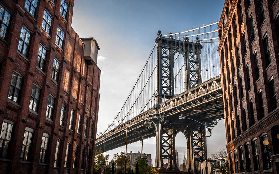 Manhattan Bridge indrammet af historiske murstensbygninger i den gyldne time. — New York Computer Wallpapers