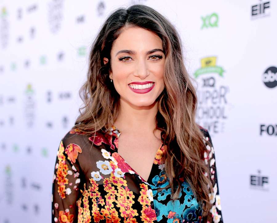 Woman in floral blouse smiling at event with branded background. — Nikki reed Wallpaper