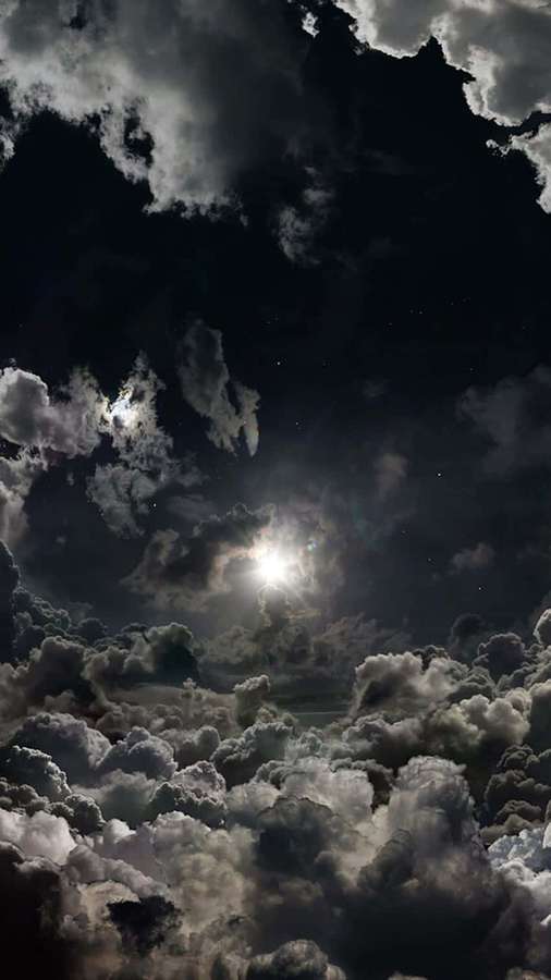 Luna brillando a través de nubes oscuras con estrellas visibles en el cielo nocturno. — Nubes Negras Fondos de pantalla