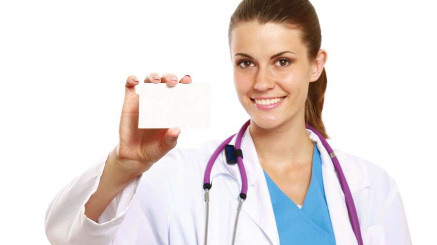 Smiling female doctor holding blank card in white coat with purple stethoscope. — Nurse Background