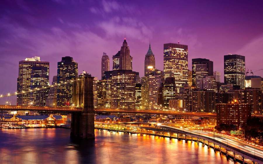 Brooklyn Bridge at night with city lights reflecting on water under purple sky — Nyc Background