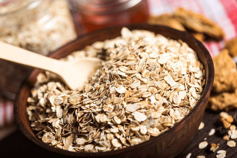 Wooden bowl of rolled oats with spoon and honey nearby. — Oatmeal Wallpaper