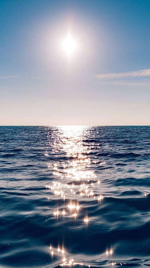 Sunlight reflecting on calm ocean waters under a clear blue sky. — Ocean iPhone Wallpaper