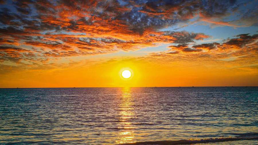 Sunset over ocean with colorful clouds and golden reflection on water — Ocean Picture