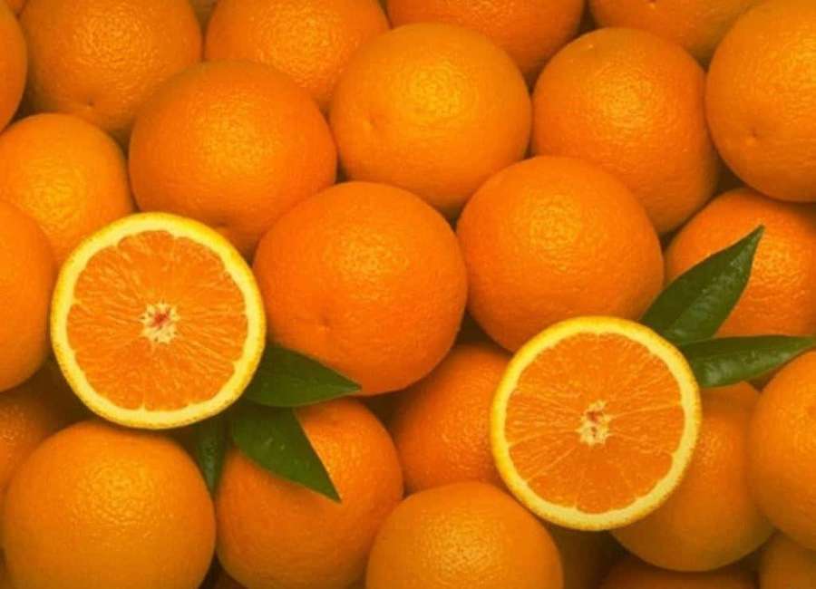 Fresh oranges with two cut halves and green leaves showing juicy segments. — Orange Fruit Background