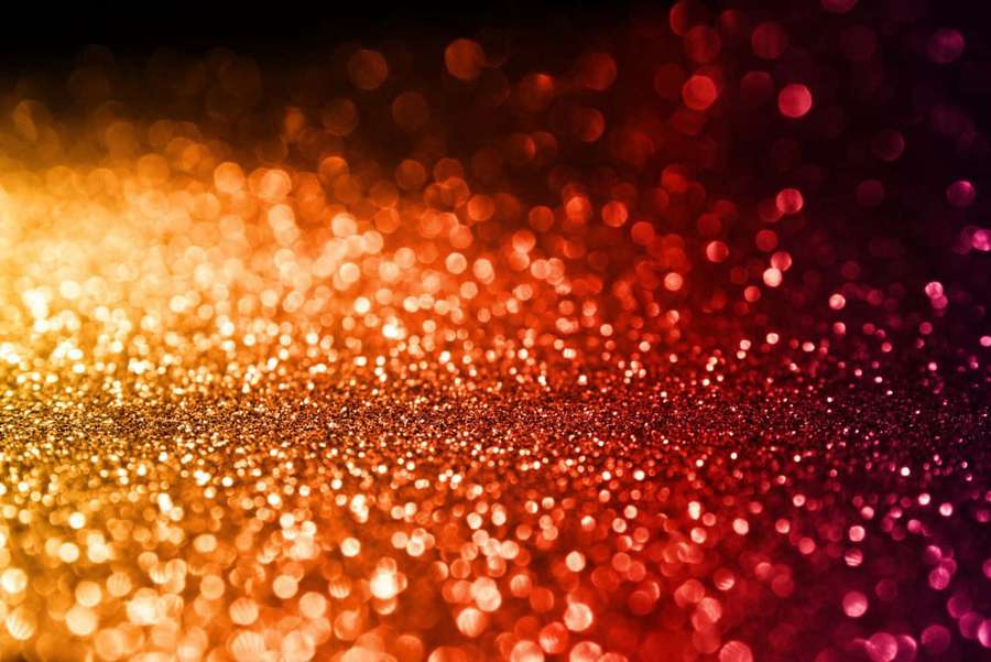 Shimmering gold to red glitter with soft blurred lights in the background. — Orange Glitter Wallpaper