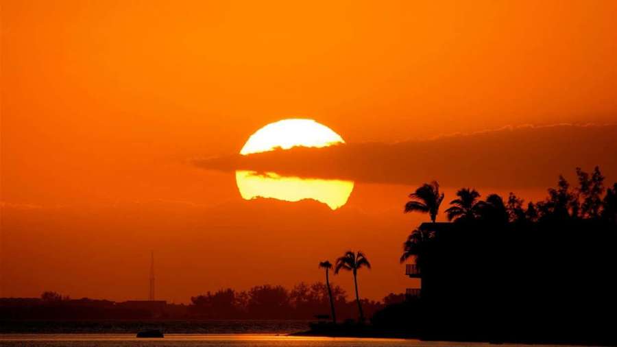 Solnedgang over vand med palmetræer og et hus i silhuet. — Orange Sunset Wallpapers