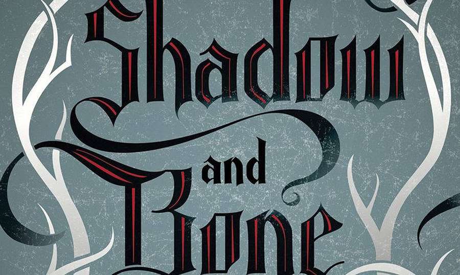 Título gótico Shadow and Bone em vermelho e preto com arabescos decorativos brancos sobre fundo cinza texturizado. — Osso Papéis de Parede