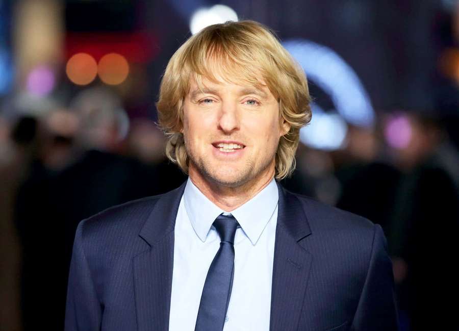 Man in dark suit smiling at camera on city night background — Owen Wilson Wallpaper