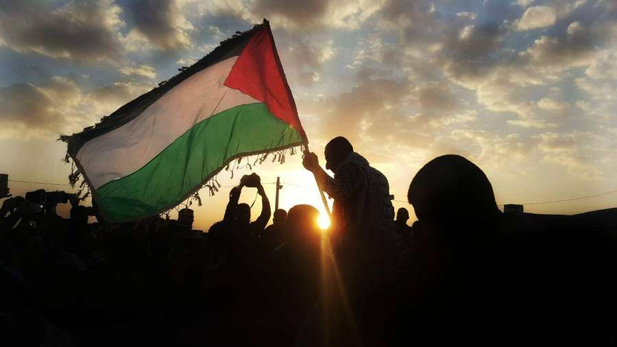 Crowd silhouetted holding Palestinian flag at sunset protest. — Palestine Wallpaper