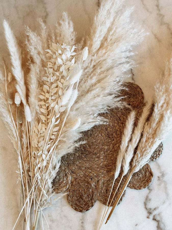 Dried pampas grass and leaves arranged on a woven mat over marble. — Pampas Grass Background
