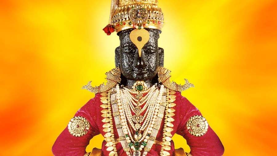 A decorated deity statue with gold ornaments and red clothing against a glowing orange background. — Pandurang Wallpaper