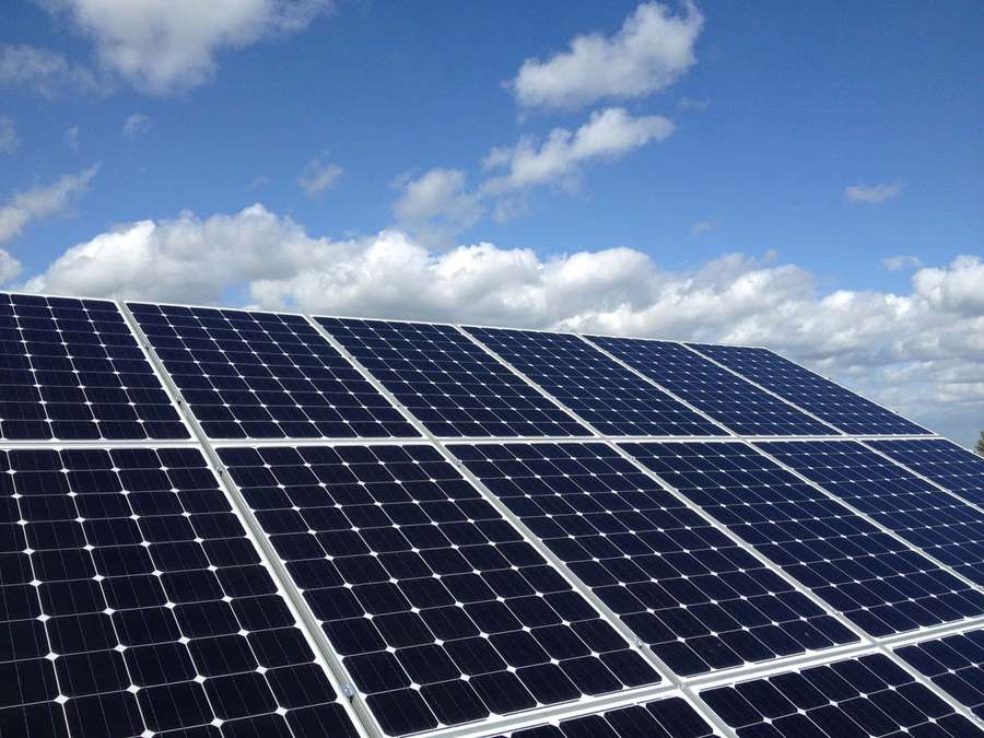 Filas de paneles solares bajo un cielo azul con nubes blancas — Panel Solar Fondos de pantalla