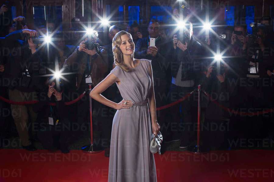 Mujer con vestido lavanda posando en la alfombra roja con fotógrafos que hacen destellar las cámaras. — Paparazzi Fondos de pantalla