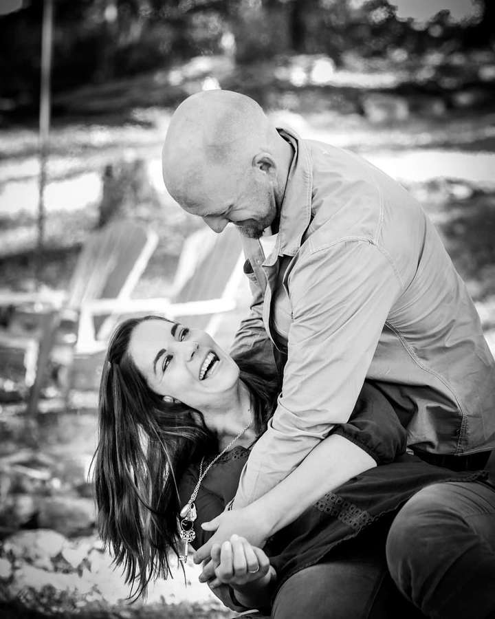 Un hombre calvo se inclina sobre una mujer riendo en un jardín. — Pareja divertida Imágenes