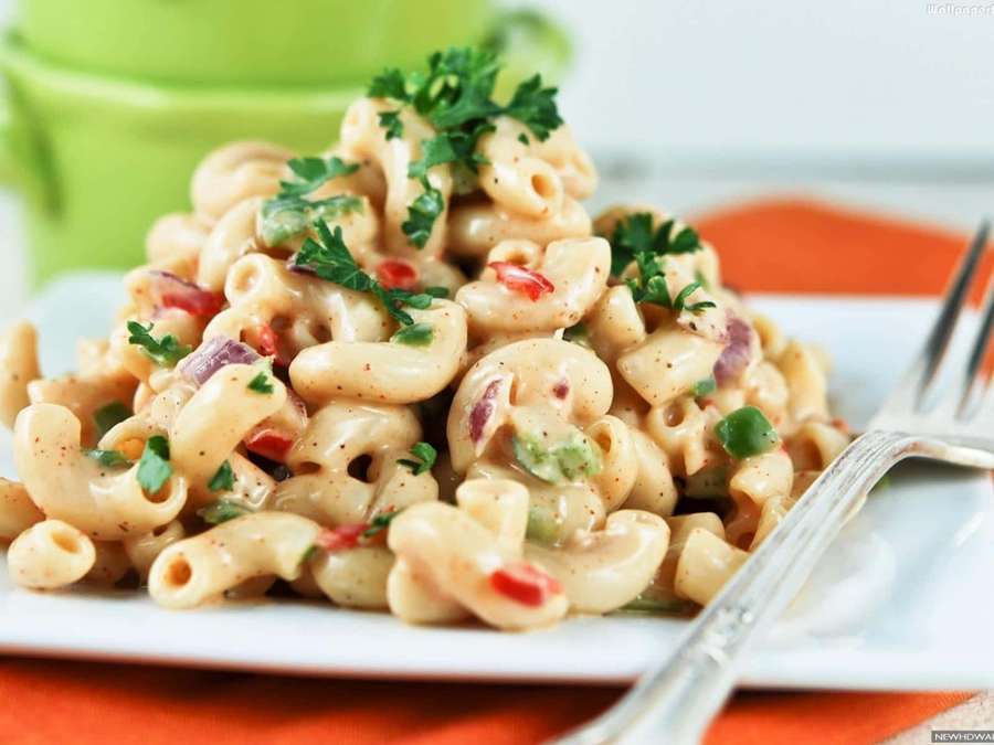 Creamy macaroni salad with parsley and red peppers on a white plate with fork. — Pasta Background